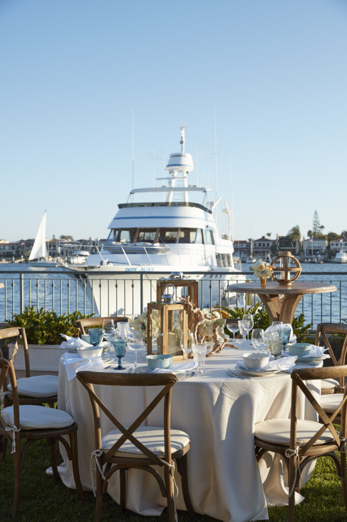 Outdoor waterfront event table with white rented linens and coastal place settings in Florida