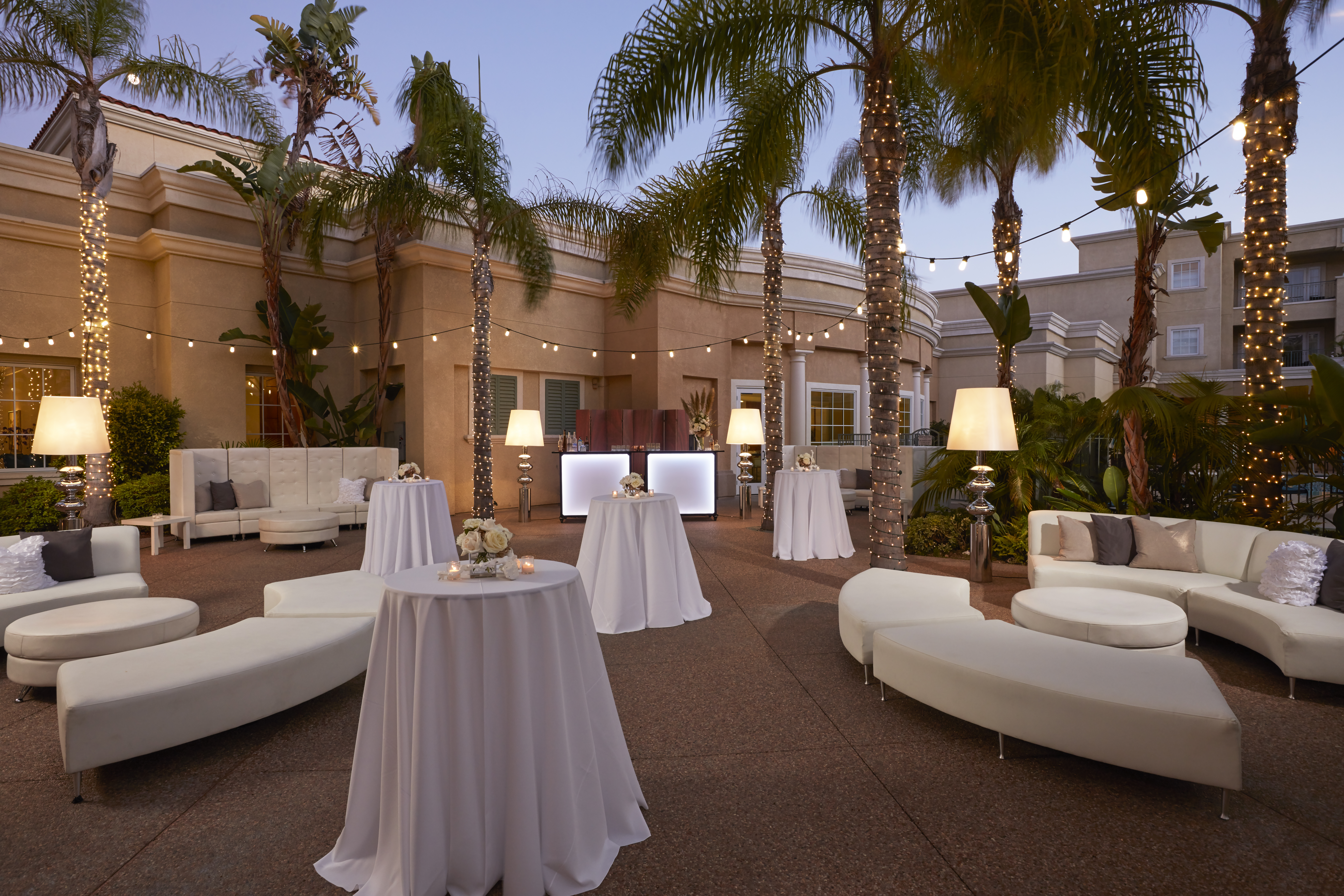 Evening resort event with linen cocktail tables under palm trees and string lights in Orlando